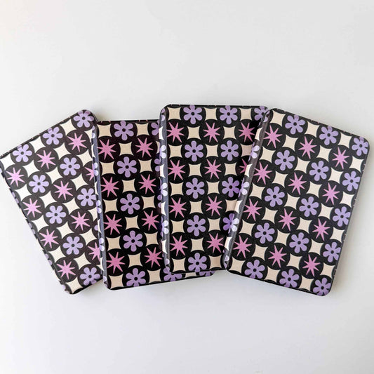 Four patterned kindle cases with purple floral and black and white geometric designs on a white background