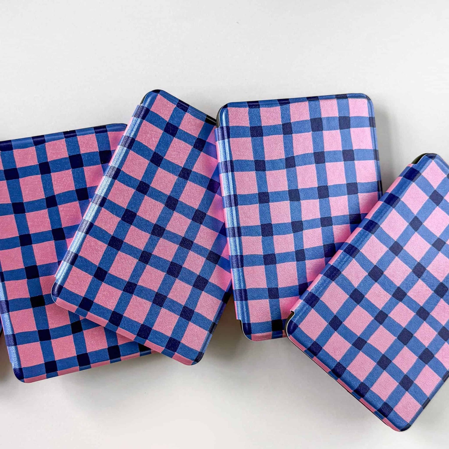 Four pink and blue gingham kindle cases on  a white background