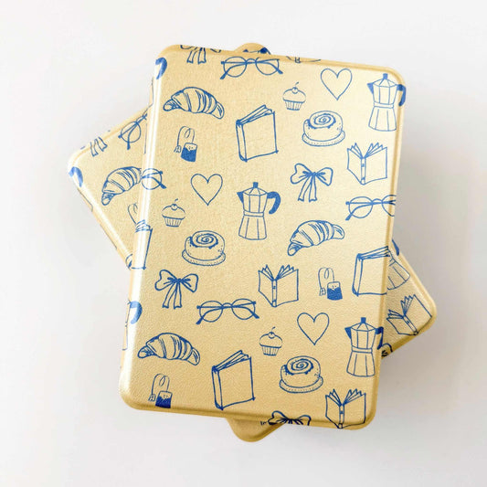 Two Yellow Kindle Cases with Blue print pattern of hearts, books, glasses, croissants, on a white background  