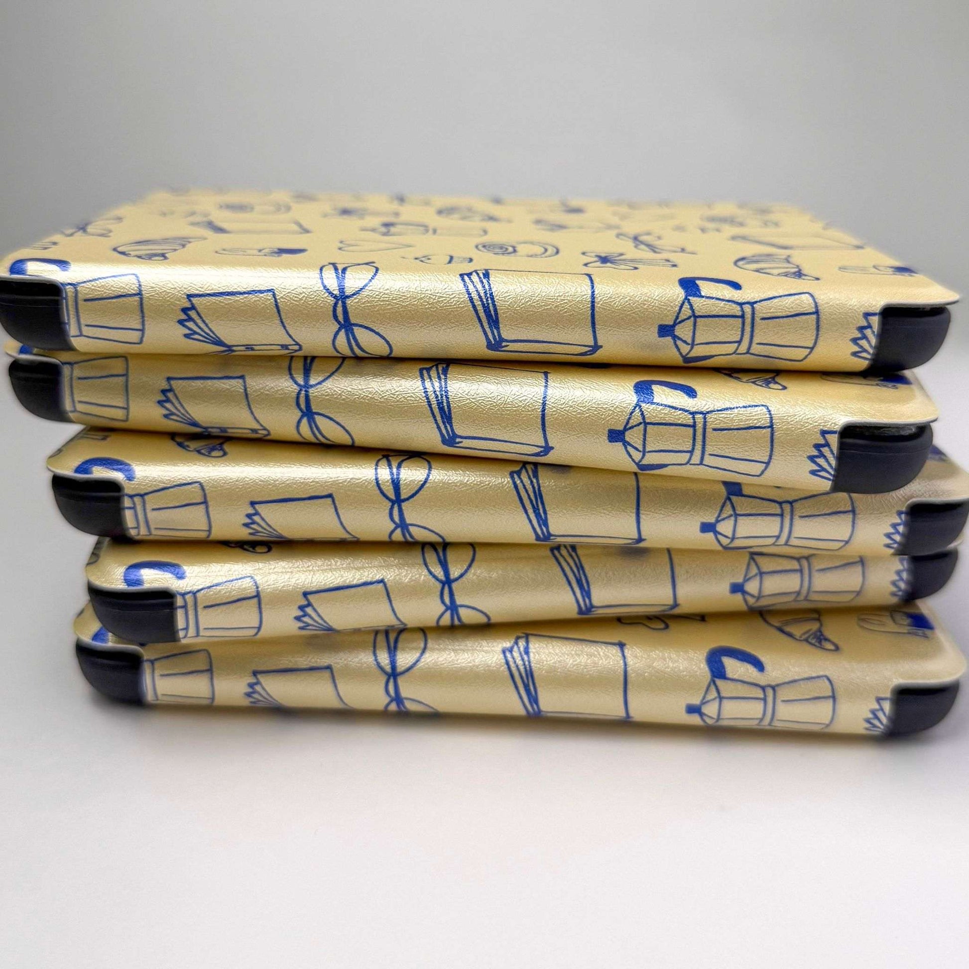Stack of yellow kindle cases with a blue print pattern, on a white background 