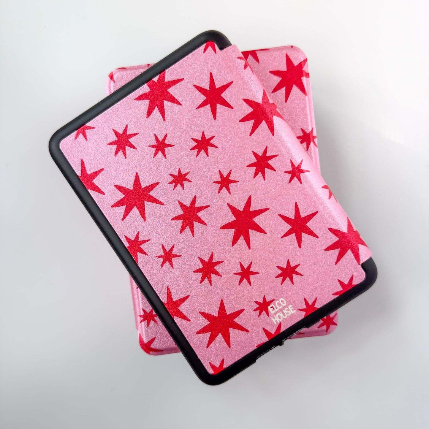 Back of pink kindle cases with red star pattern, and black border on a white background with the words "ELCO HOUSE" written on back of kindle case 