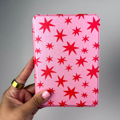 Pink case with red star pattern held by a hand against a gray background