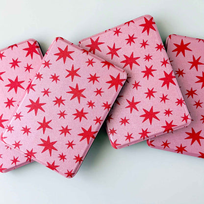 Kindle cases printed with red stars on a pink background. Kindle cases are spread out on a white background 