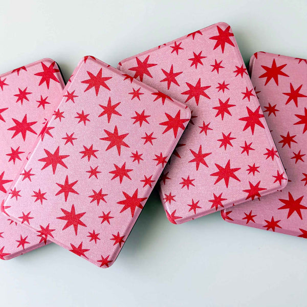 Kindle cases printed with red stars on a pink background. Kindle cases are spread out on a white background 