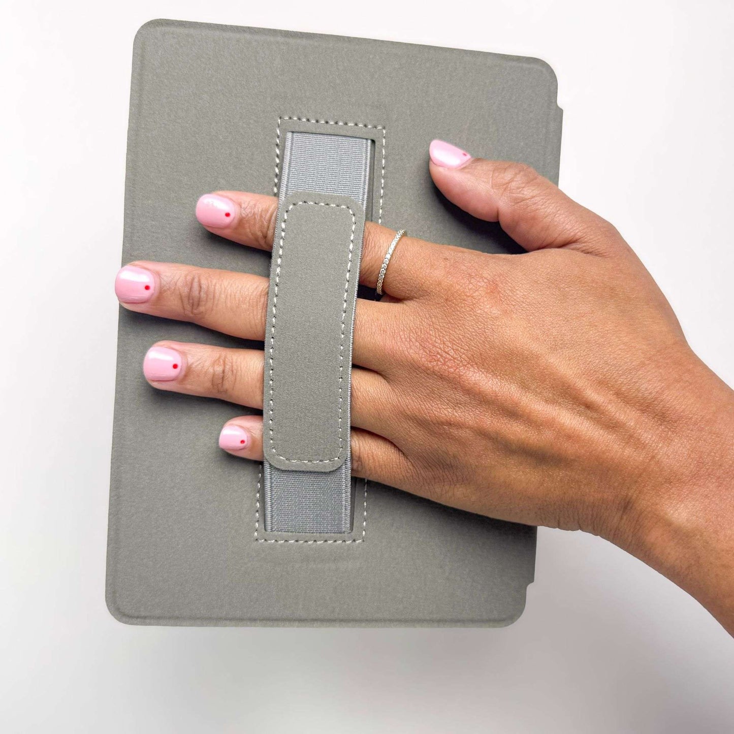 Hand holding a gray fabric-bound kindle case with a strap on a white background