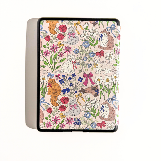 A Kindle Case featuring a colorful floral and animal print on a light pink background. The print includes illustrated flowers, butterflies, and cats in red, blue, green, orange, and brown.
