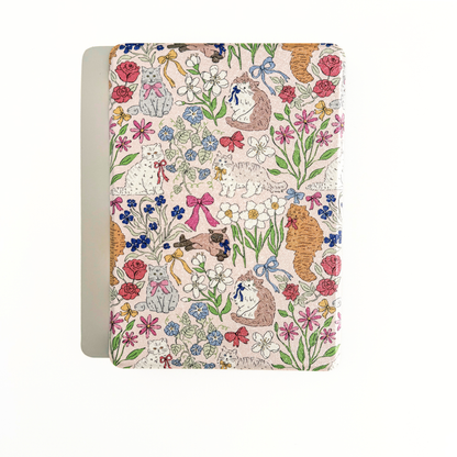 A Kindle case with a whimsical, vintage-style floral and animal pattern on a cream-colored cover, shown against a plain white background.