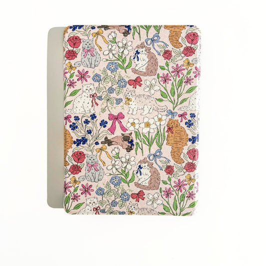 A Kindle case with a whimsical, vintage-style floral and animal pattern on a cream-colored cover, shown against a plain white background.