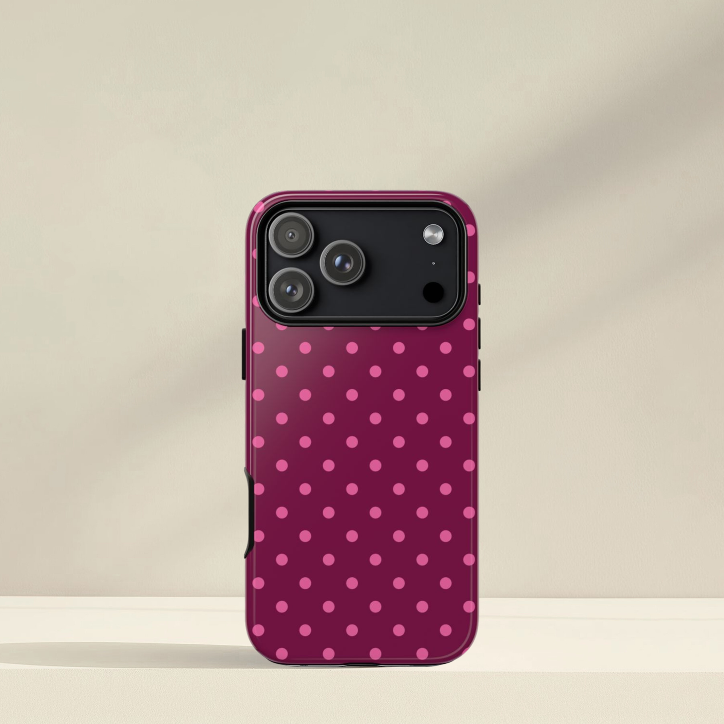 Phone case with pink polka dot pattern on a beige background