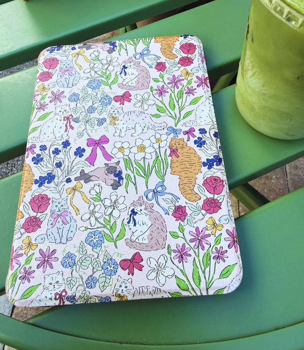 Floral and cat patterned Kindle case on a green table
