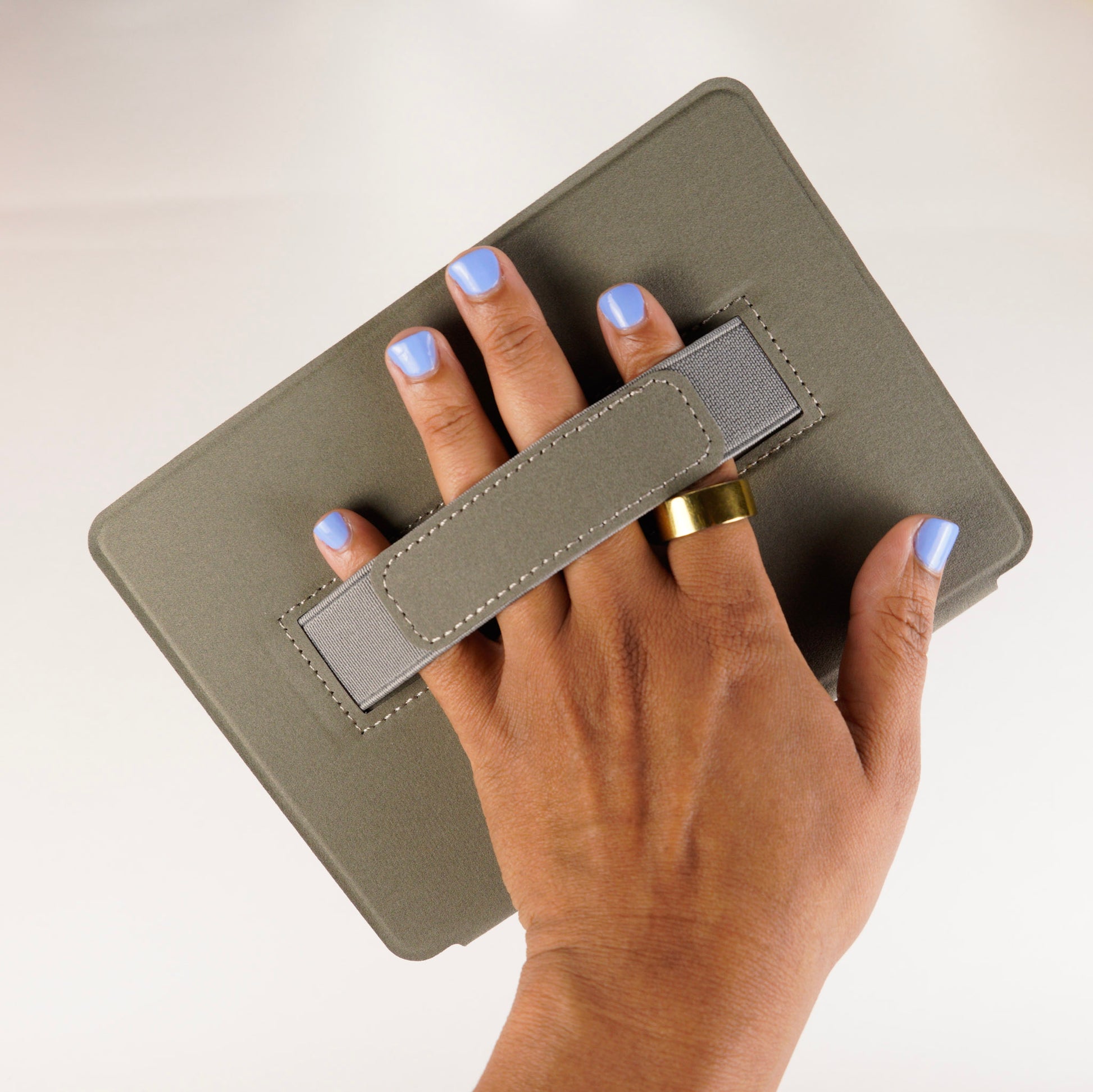 Hand holding inside of kindle case with grey strap 