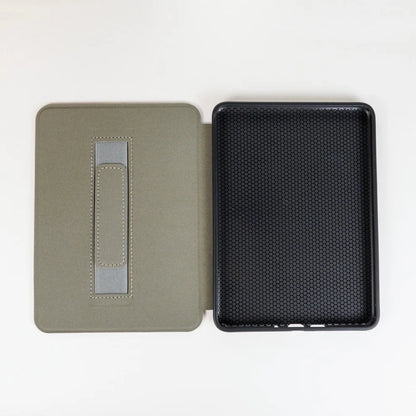 Inside of open kindle case, left side gray with hand strap and the right side is black with a grid texture, on a white background.