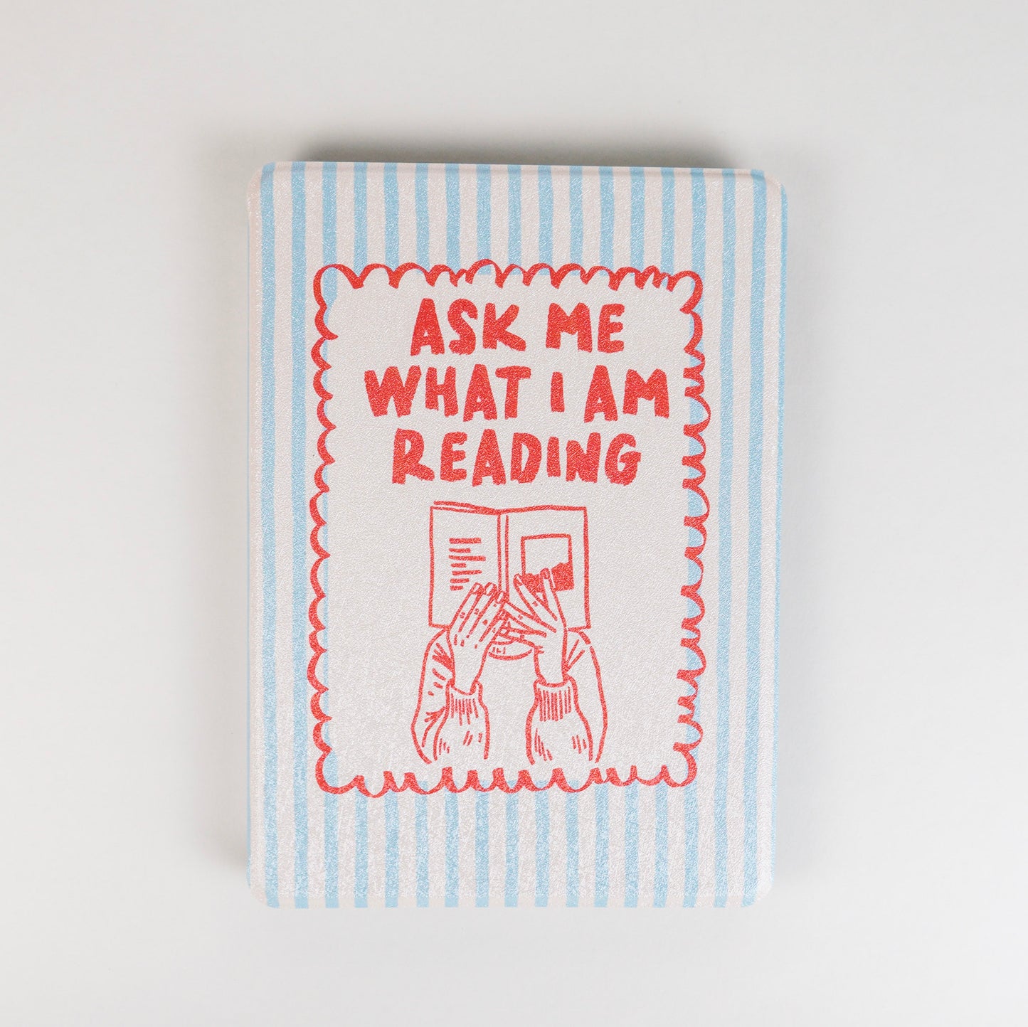 Page Turner Kindle Case with blue and beige stripes, red text that says ‘Ask Me What I Am Reading,’ and hands holding a book illustration by Elco House